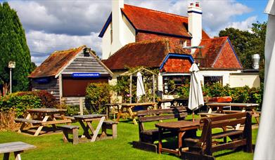 The Countryman Inn outside seating area, a grassy space with picnic tables and a red roofed pub building