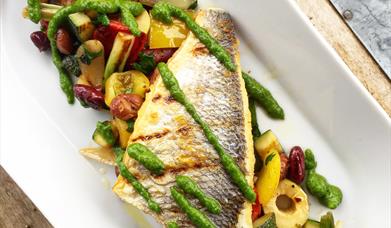 image of a long dish with a fillet of grilled fish on a bed of vegetables