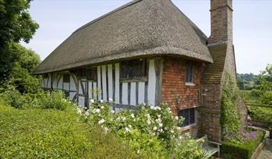 National Trust Alfriston Clergy House with thatched roof, high chimney stack and cottage garden