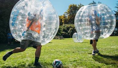 inflatable football, two players wearing inflatable ball shaped suits kicking a ball