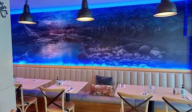 inside the restaurant showing tables and a large picture on the wall