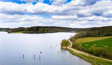 ardingly reservoir lake, with walking path around edge and paddle boarding on the water