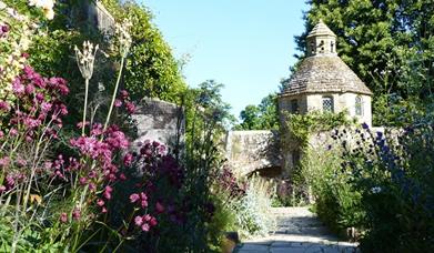 a pathway through the walled garden leading to a tower building
