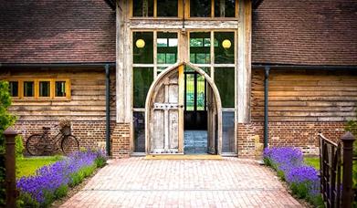 entrance to kingscote - wooden arched door frame with purple flowers lining the path