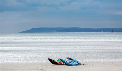 a kitesurf sail on the beach with a long sandy stretch to the water's edge