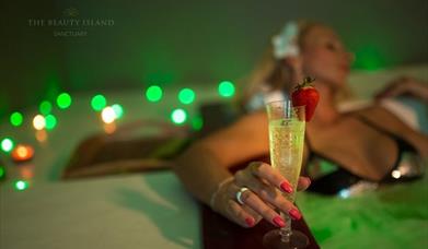 a woman relaxing in subdued lighting with a glass of bubbly