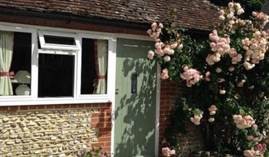 A small farmhouse with roses around the door