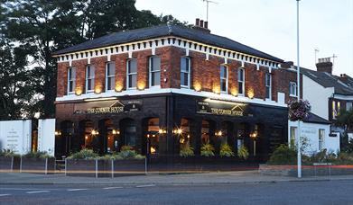 The Corner House in Worthing image shows brick buillding with black painted external lower walls with glowing uplights
