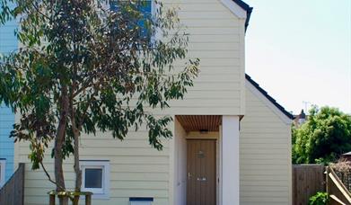 Yellow cottage with large tree in front garden, one of Sussex Coast Cottages