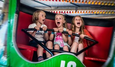 three children on a ride with happy but screaming faces