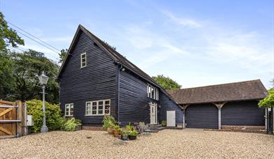 a barn building in dark wood with a gravel driveway