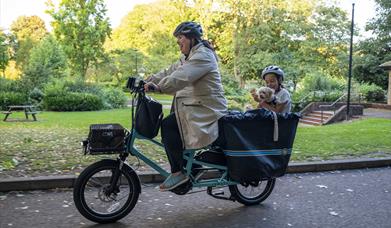 person riding a bicycle with a child in a hamper on the back