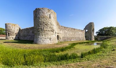 Pevensey Castle walls and round towers with field in the foreground