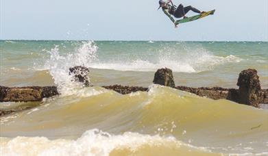 a kitesurfer in the air with waves