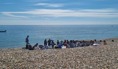 Group on the beach in the sunshine having a safety briefing before heading into the water