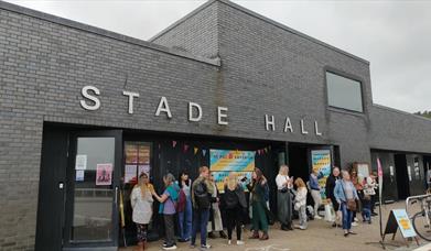 A photograph of Stade Hall, with people waiting outside