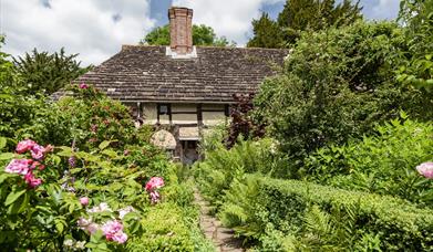 a garden in bloom with the priests house in the background