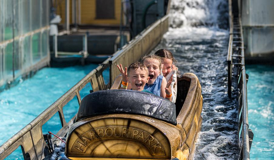 three children on a water chute ride with happy but screaming faces