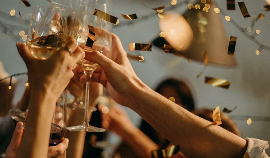 Golden confetti showering on party with wine glasses