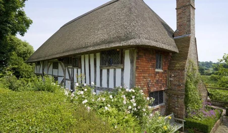 National Trust Alfriston Clergy House with thatched roof, high chimney stack and cottage garden
