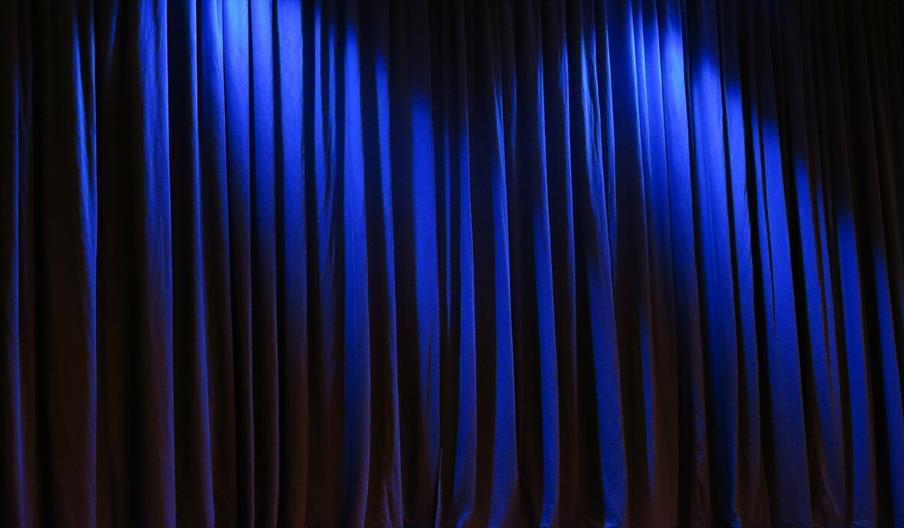Dark blue stage curtain with light shining from spotlights above