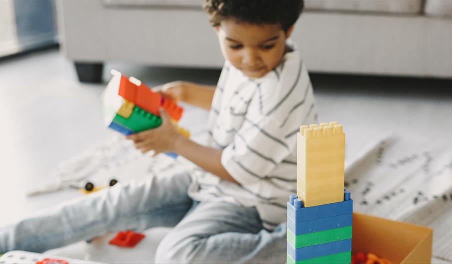 A child playing with colourful plastic building bricks