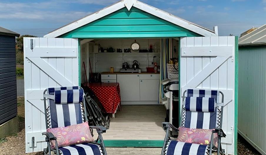 A view of the inside of a beach hut with chairs outside