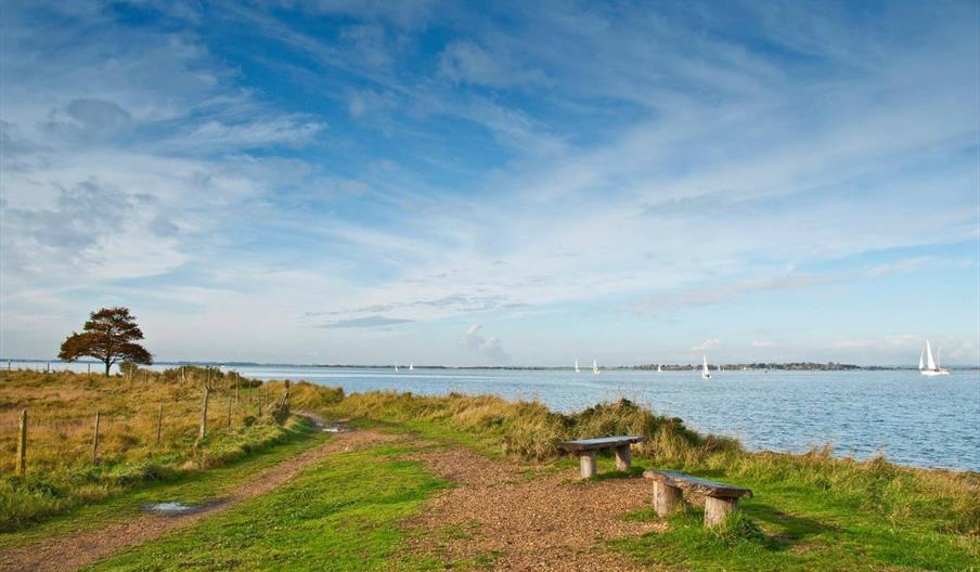 waterside walk with yachts in the distance on water.