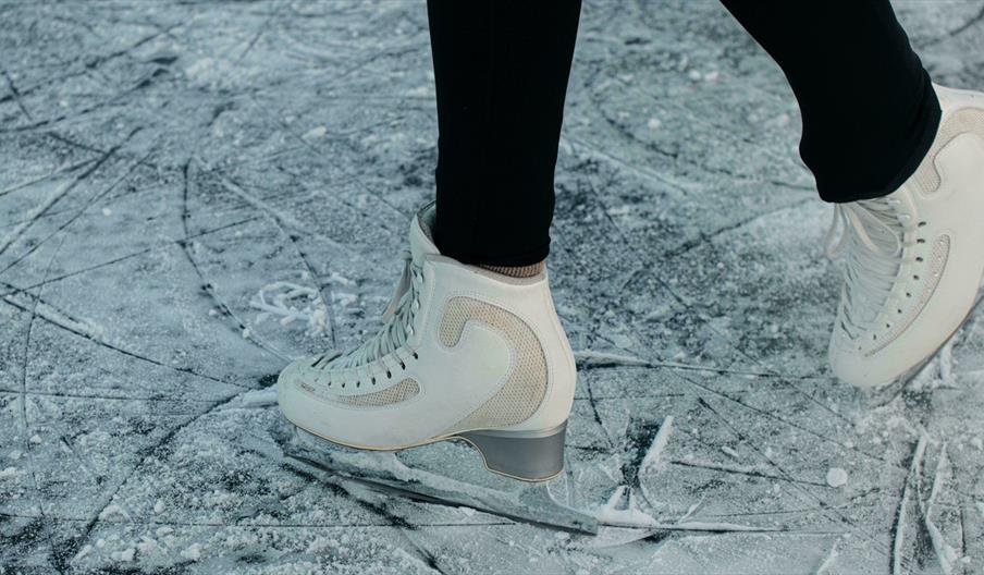 Person in white figure skates on fresh ice