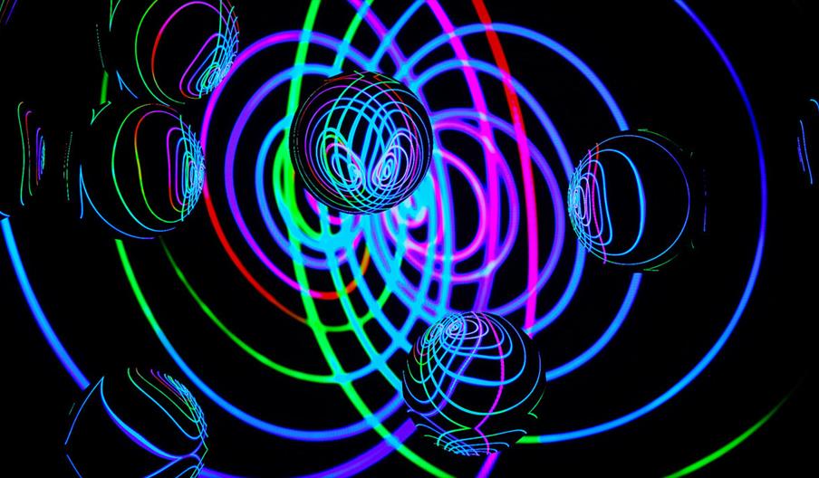 Bubbles reflecting neon circles against a dark surface