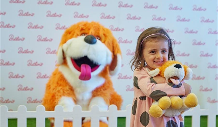 A child hugging a teddy with a giant dog soft toy