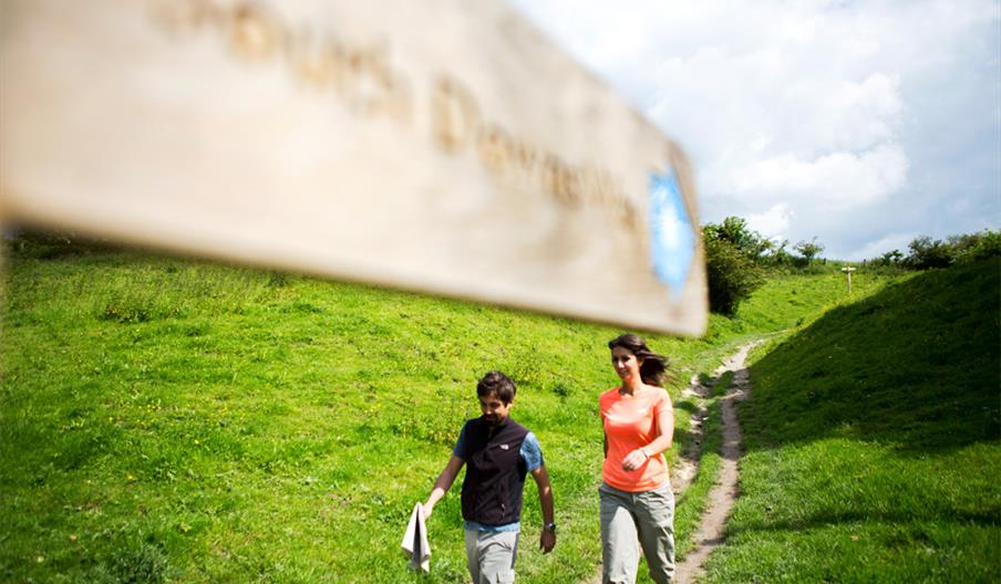 two poeple walking on the downs with a map in their hands