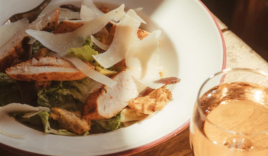 a bowl with a fresh salad and a glass of rose wine
