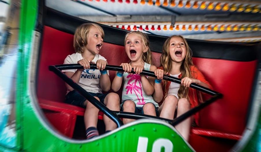 three children on a ride with happy but screaming faces