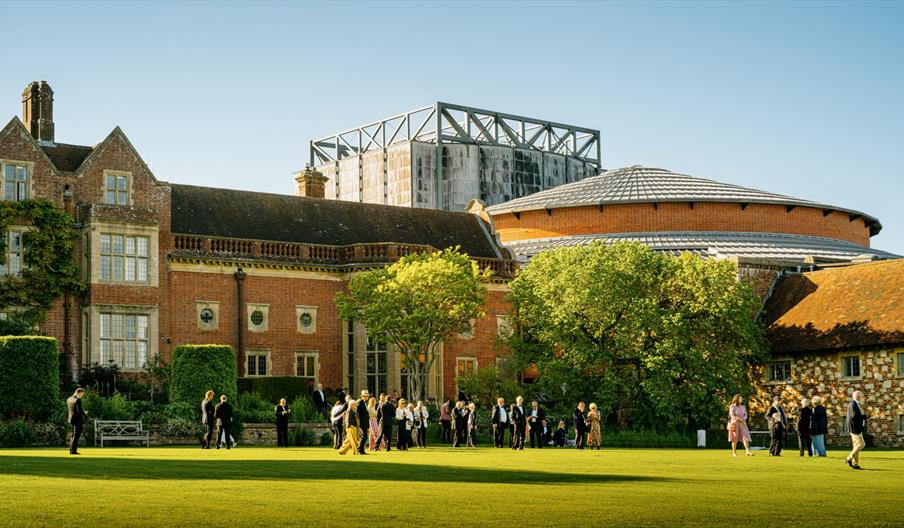 The exterior of the opera house, with guests milling around on a bright grassy area