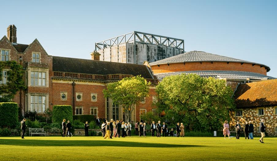The exterior of the opera house, with guests milling around on a bright grassy area