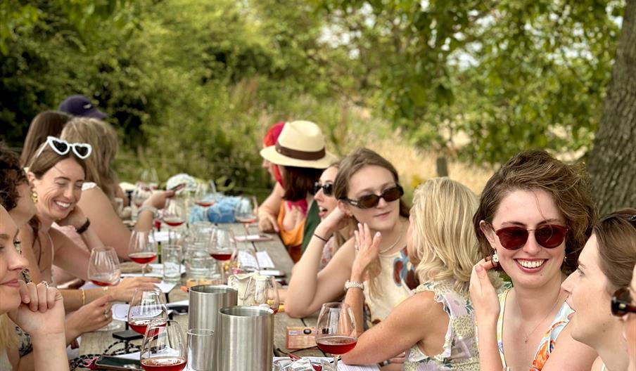 group of friends drinking wine outside on a Sussex vineyard