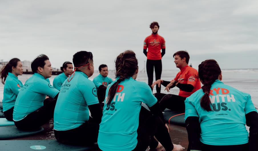 surf school lesson - people sitting on their boards listening to an instructor