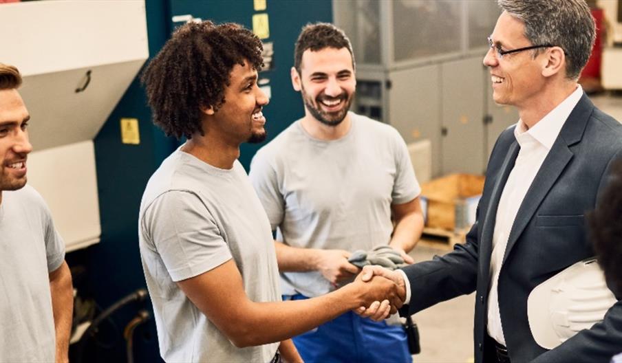 people standing around two more people shaking hands