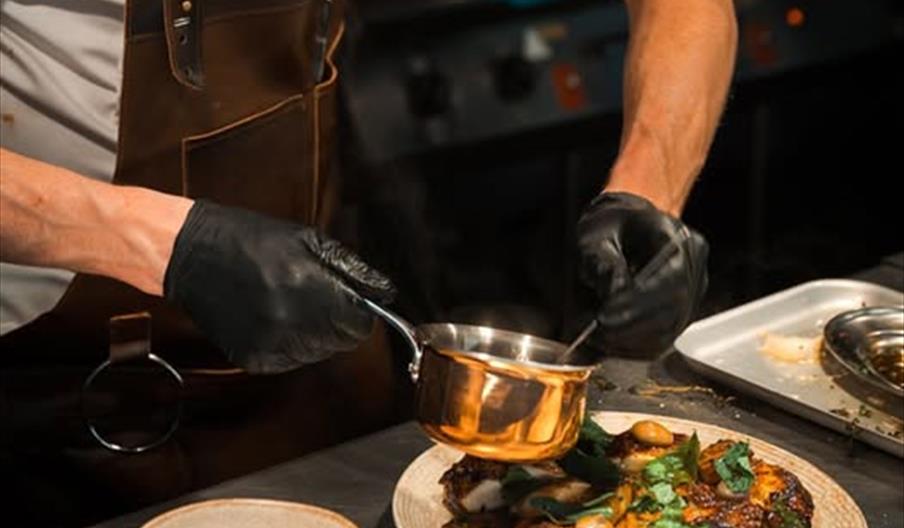 close up of chef dressing a plate of food