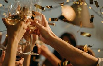Golden confetti showering on party with wine glasses