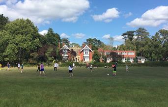 view of the hall from the garden with young people playing football