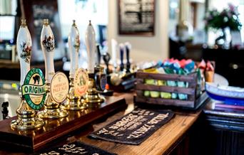 4 traditional pull style beer pumps showing real ales on a wooden pub bar with beer mats at The Cat Inn