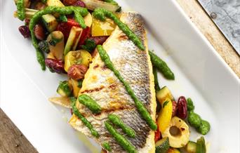 image of a long dish with a fillet of grilled fish on a bed of vegetables