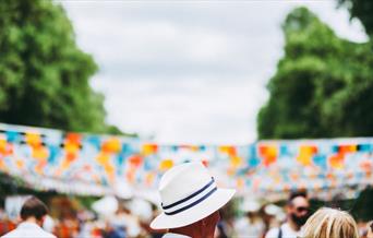 Person in white hat in front of blue and orange bunting