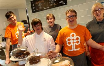a group of staff smiling for camera in front of the cakes displays