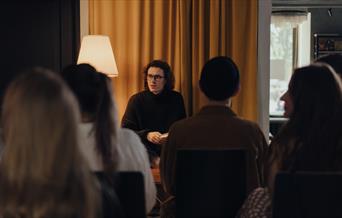 Long haired individual talking to a crowd