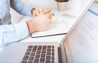 White laptop and man writing in notebook