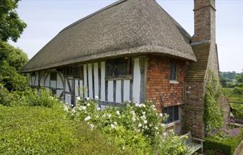 National Trust Alfriston Clergy House with thatched roof, high chimney stack and cottage garden