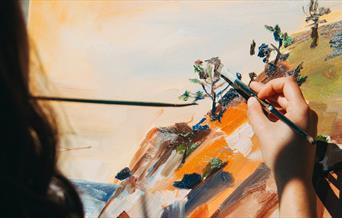 Woman painting a nature scene outside
